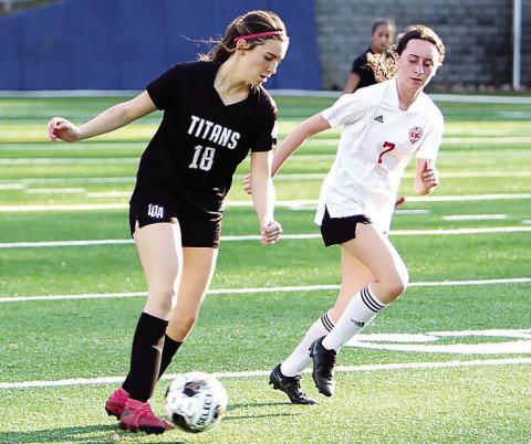 LOA freshman Addison Kelley (18) dribbles the ball away from a GMC Prep defender. LANCE McCURLEY/Staff