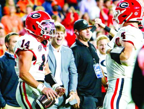 Georgia quarterback Gunner Stockton (left) celebrates with tight end Oscar Delp (right) after icing the game with a 10-yard touchdown run late in the fourth quarter against Auburn. LANCE McCURLEY/Staff