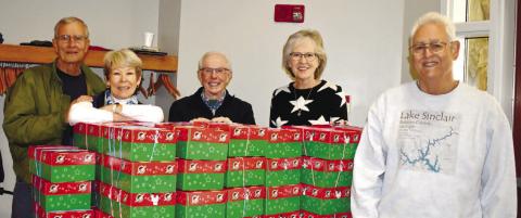 Alongside stacks of OCC shoeboxes at Lake Oconee Lutheran Church in Eatonton are (L-R): volunteers Barney Ross, Sharon Ross, Tom Mathson and Margaret Pederson with Gary Stevens from First United Methodist Church, who had just delivered more boxes.