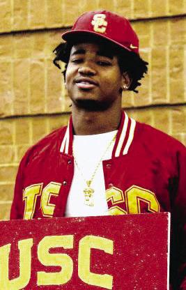 Steve Miller holds up a USC painting after he signed with the Trojans on Dec. 4, 2024, at a ceremony held in the Greene County High School cafeteria. LANCE McCURLEY/Staff