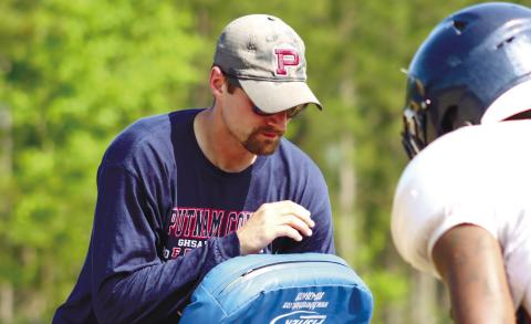 Beasley (left) coaches up a Putnam County player during blocking drills at practice this past spring. LANCE McCURLEY/Staff