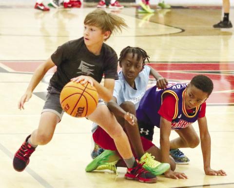 A youth camper dribbles by a few of the others during a scrimmage game in the Bulldogs’ gymnasium. BRENDAN KOERNER/Staff