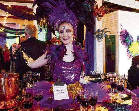 A performer at one of two “living tables” provided wine and ArtiGras beads to guests at The Livery before the party moved next door to Barrel 118. IAN TOCHER/Staff
