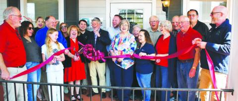 Licensed speech therapist Kay Jones (red dress), owner of Lake Oconee Speech Therapy, cuts the ribbon flanked by her husband and son as other members of her Lake Country community cheer the official opening of her facility at 951 Harmony Rd., Ste. 103, Eatonton. IAN TOCHER/Staff