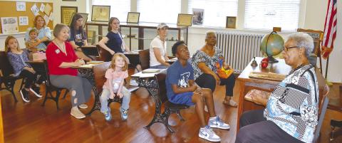 Georgia Benjamin-Smith of Mothers Against Crime tells stories of the past to eager listeners in the old classroom at the Old School History Museum.