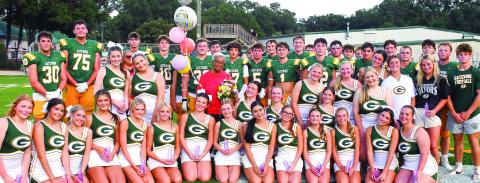 Gatewood cheerleaders and football players surround Eatonton icon Georgia Benjamin-Smith (in red) on her 85th birthday, following a brief pre-game candlelight vigil she organized to bring awareness to local domestic violence issues. IAN TOCHER/Staff