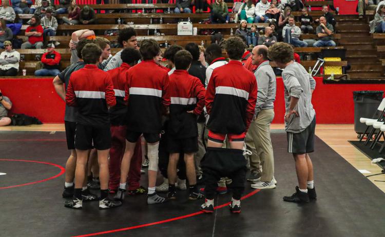 The Mat Dogs gather around head coach Jared Rector to discuss strategy during a match last season at Stephens County High School. LANCE MCCURLEY/Staff