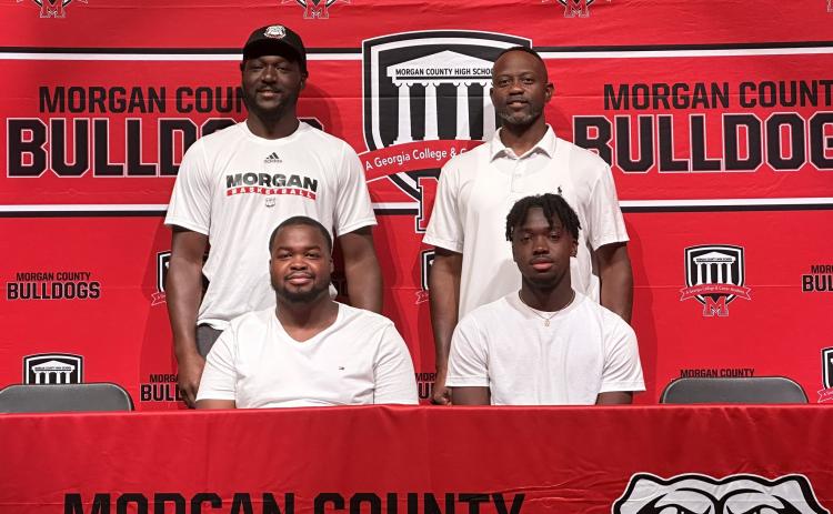 Jaturi Brown (front row - left) and TJ Thomspon (front row - right) with two Morgan County assistant coaches at their signing ceremony on Wednesday, July 12. CONTRIBUTED