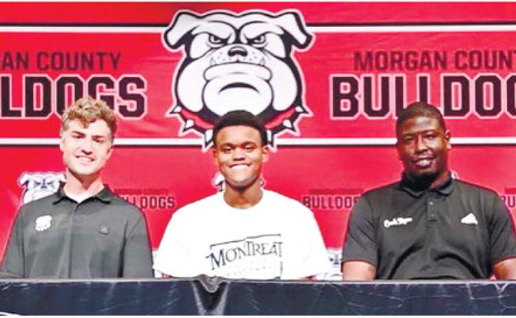 Morgan County senior Shawn Morgan (center) with Bulldogs’ head coach Cody Anderson (left) and assistant Vincent Rogers (right) during his signing ceremony. CONTRIBUTED