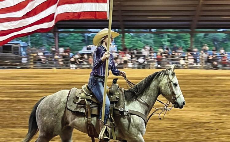 A rodeo performer carries the American flag during the presentation of flags. (CONTRIBUTED)