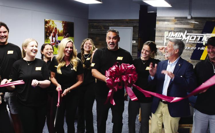 Greene County residents Dana and Dr. Pablo Santamaria (center, with scissors and bow) opened InMotion Wellness initially based on Pablo’s exposure to the benefits of targeted, assisted stretching after undergoing an operation to correct a painful back condition.