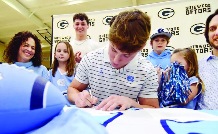Surrounded by his family, including mother Christine and his father, Dan, Evan Bennett put pen to paper on his commitment contract with the University of North Carolina last Wednesday in Eatonton. IAN TOCHER/Staff
