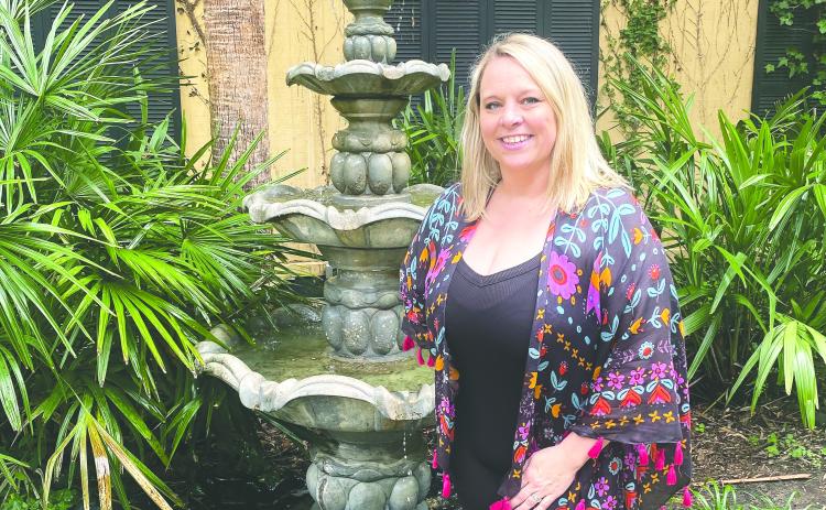 Nicole Green stands among the palms and fountain in the courtyard of The Palms on Main. MAUREEN STRATTON/Staff