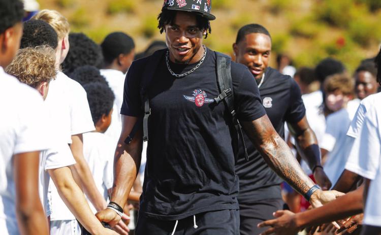 Jalon (center) and Gerald (behind) give campers high-fives after being introduced before the event. LANCE MCCURLEY/Staff