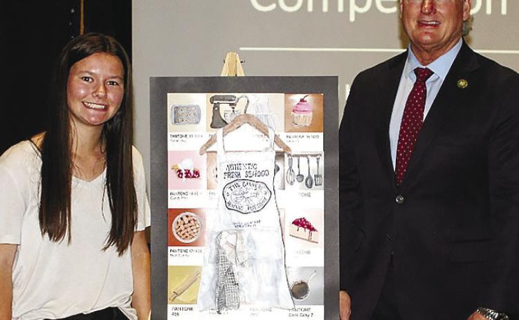 Mary Claire McCommons stands beside her color pencil and acrylic work “Elements of Baking” with District 10 Representative Mike Collins. CONTRIBUTED