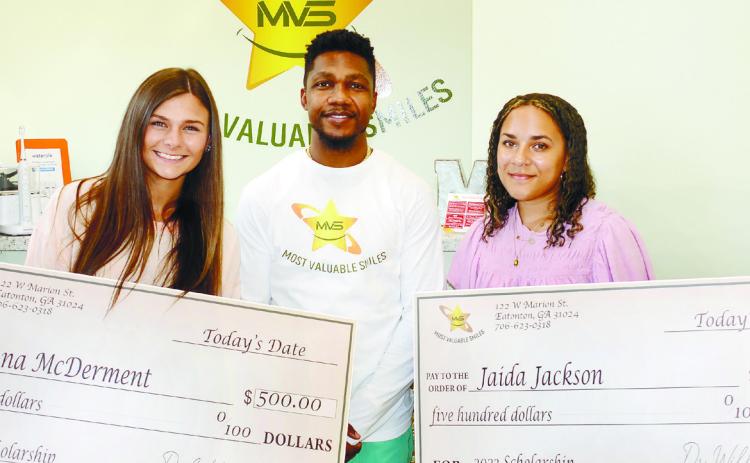 Dr. Willie Oliver of Most Valuable Smiles, presented Putnam County High School graduates Jenna McDerment (left) and Jaida Jackson with $500 scholarship checks last Friday. IAN TOCHER/Staff