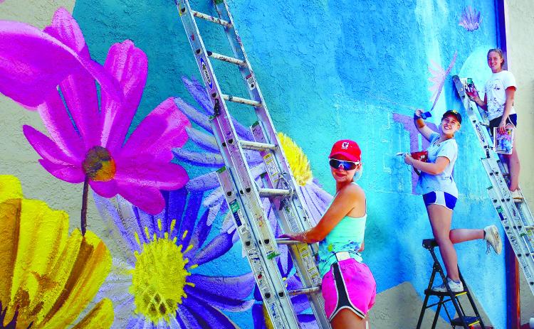 Painters work on a new mural in downtown Eatonton during the Dairy Festival, bringing color to the side of the building that houses Nails by Aaron at the corner of North Jefferson Avenue and Marion Street. IAN TOCHER/Staff