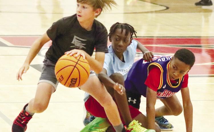 A youth camper dribbles by a few of the others during a scrimmage game in the Bulldogs’ gymnasium. BRENDAN KOERNER/Staff