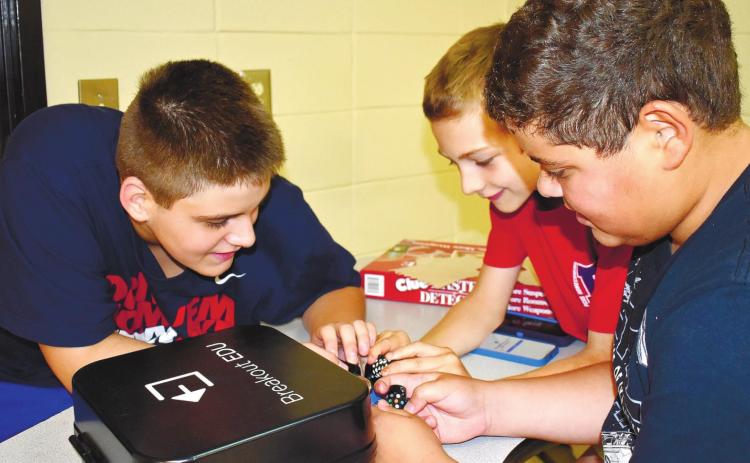 From left, fifth graders Noah Hulett Sinohul, Alexander Rochau and Ian Ortiz work on unlocking the coded lock.